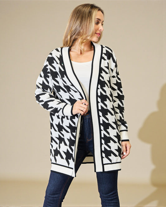 Woman wearing a black and white patterned cardigan against a beige background