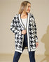 Woman wearing a black and white patterned cardigan against a beige background