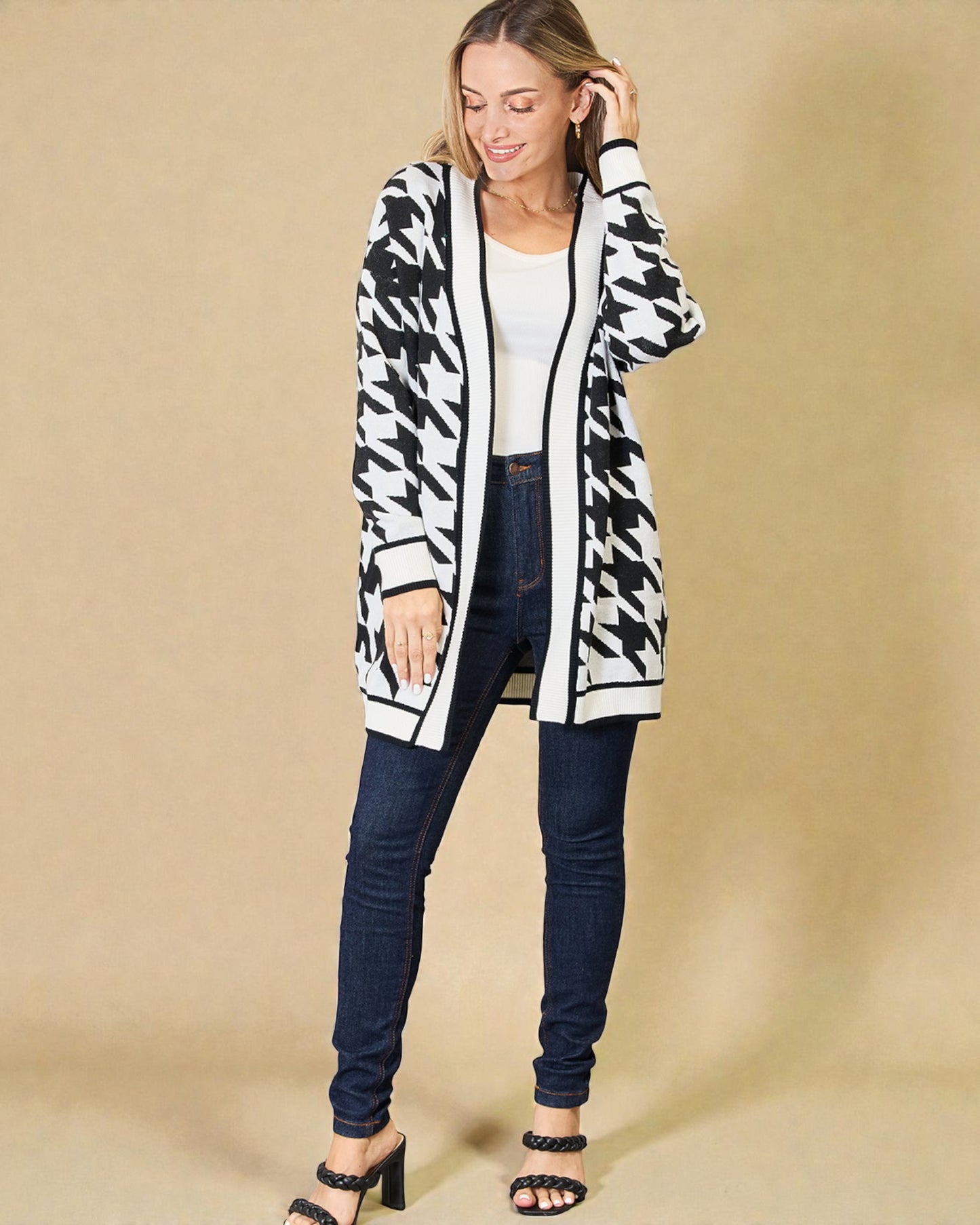 Woman wearing a black and white houndstooth patterned cardigan on a beige background