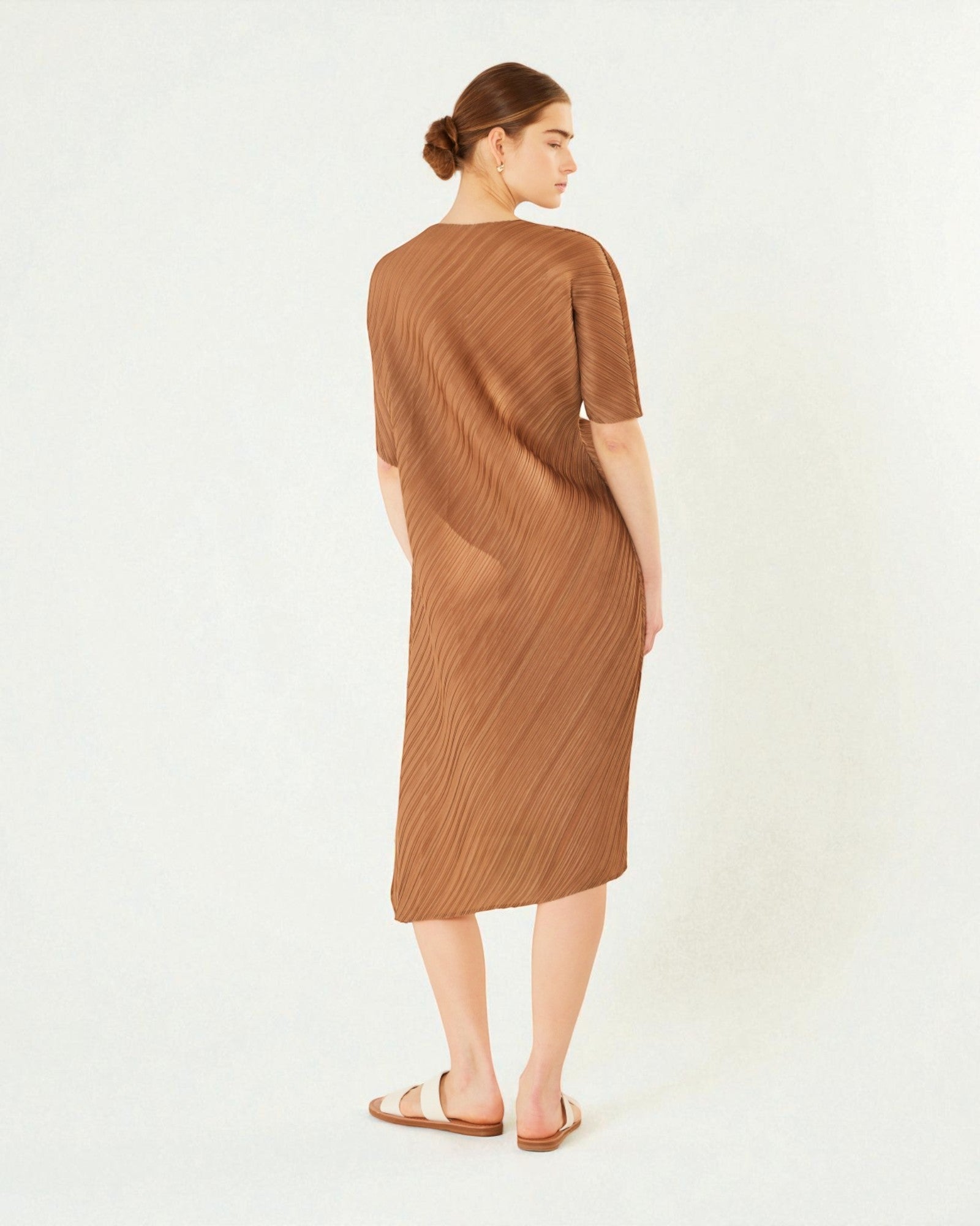Woman wearing a brown pleated dress on a white background