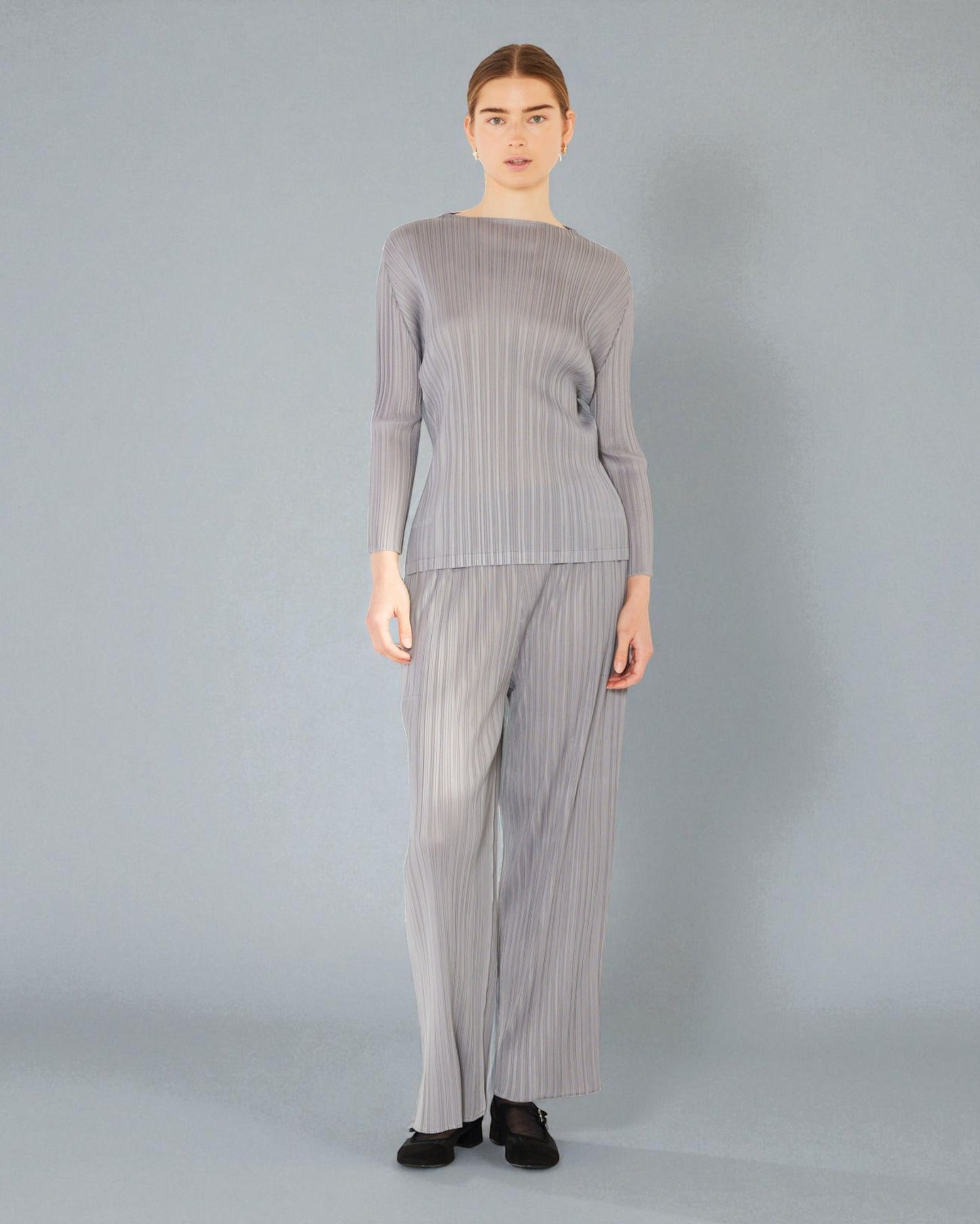 Person wearing a gray ribbed sweater and matching pants on a gray background