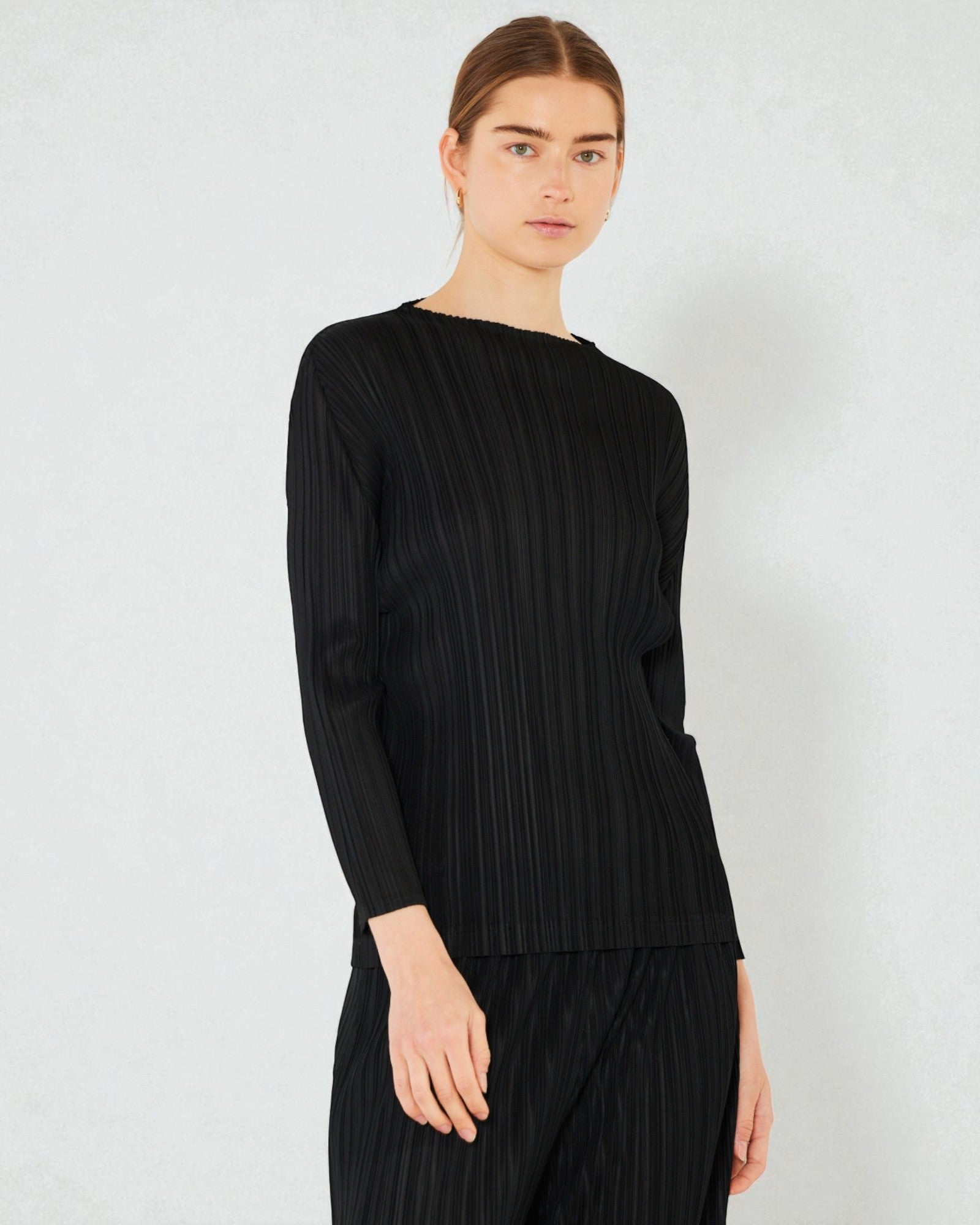 Person wearing a black ribbed sweater and pants on a white background