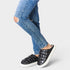 Black quilted sneakers worn with blue jeans on a light gray background