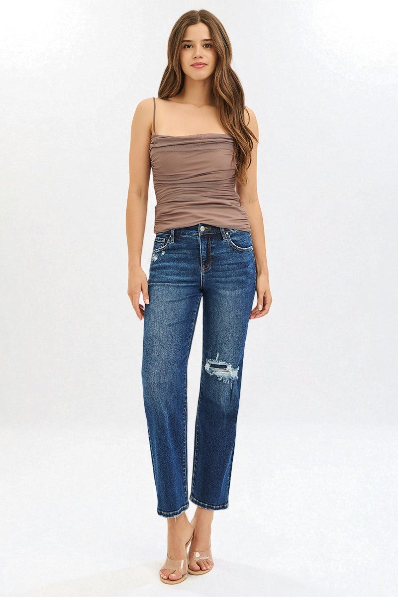 Woman wearing a brown top and blue jeans on a white background