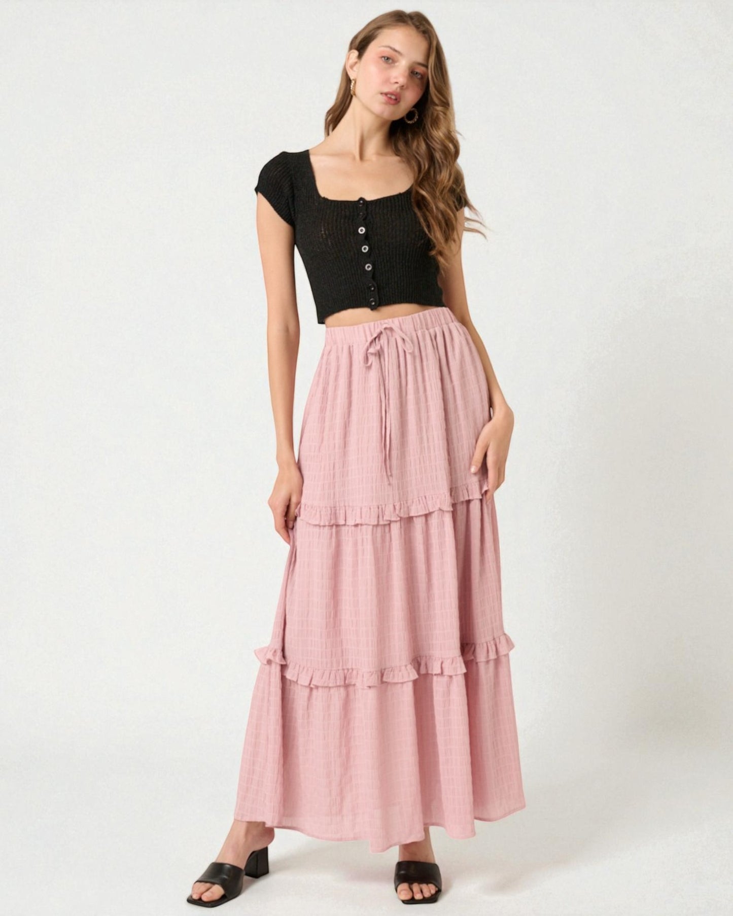 Woman wearing a black top and pink tiered skirt on a white background