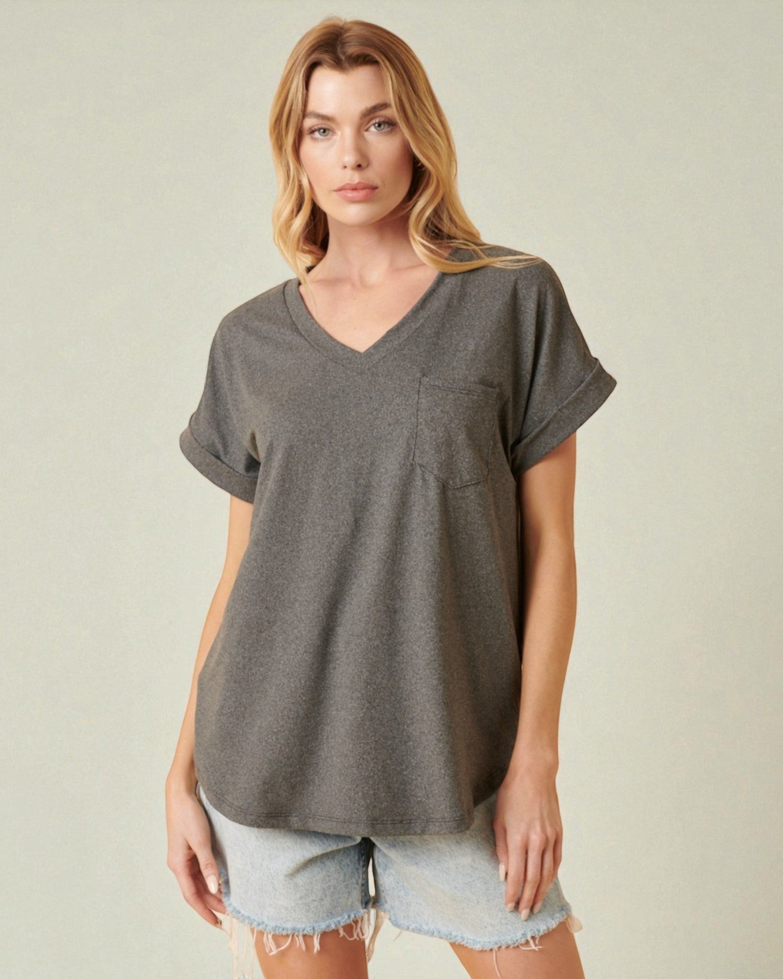 Woman wearing a gray t-shirt and denim shorts on a plain background