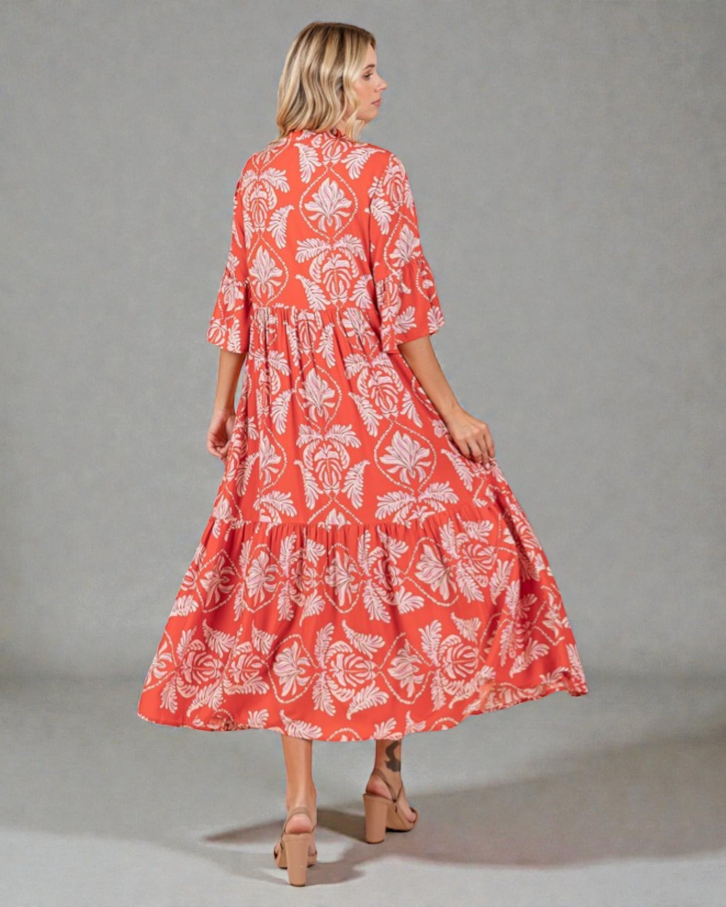 Woman wearing a red floral dress on a gray background