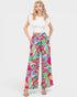 Woman wearing colorful patterned pants and a white top on a white background