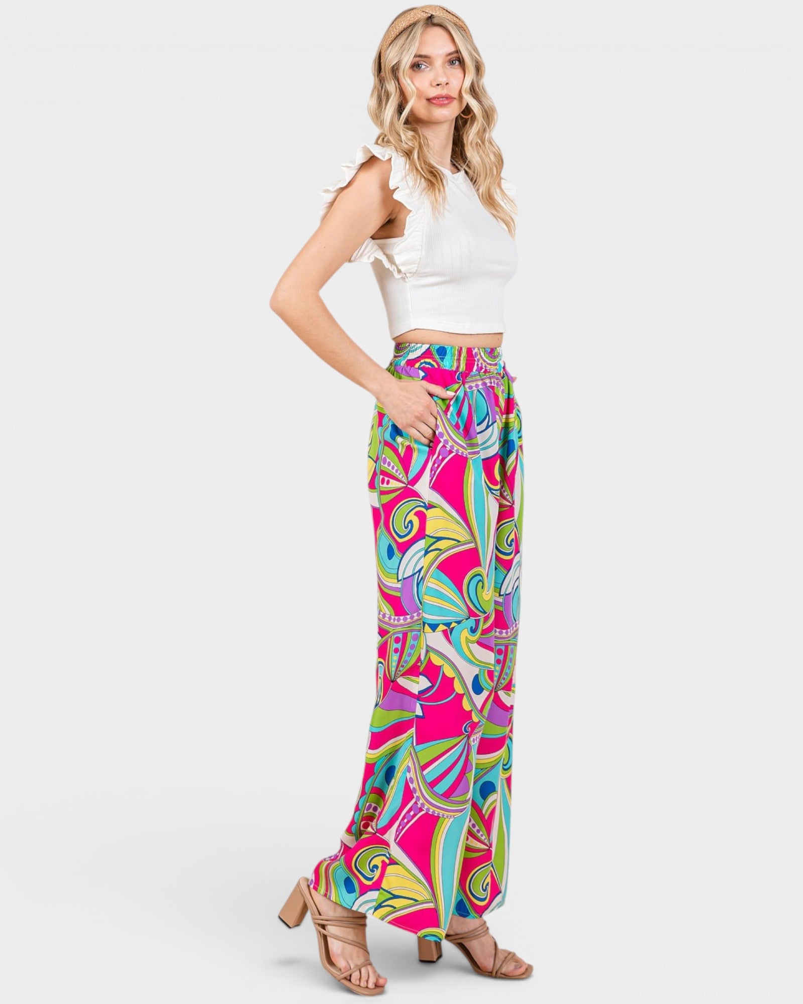 Woman wearing a white top and colorful patterned pants on a white background