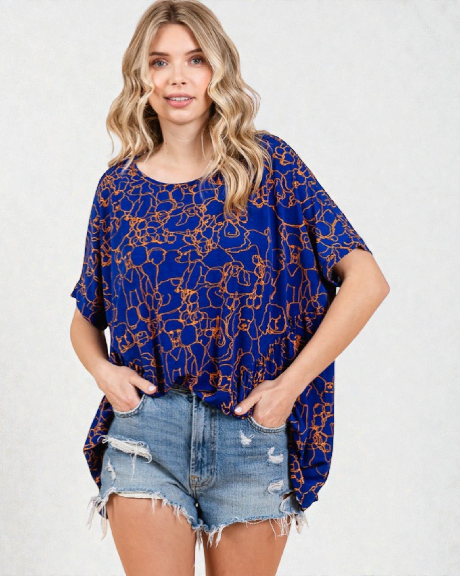 Woman wearing a blue patterned top and denim shorts on a white background