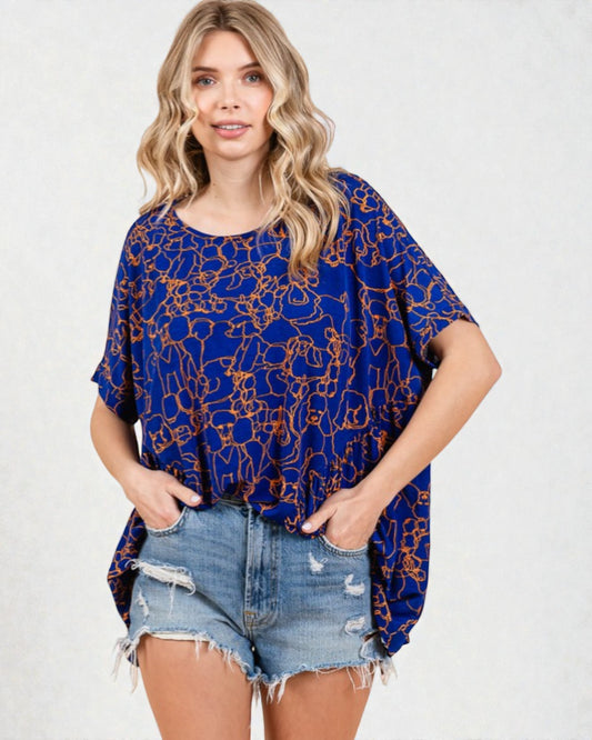 Woman wearing a blue patterned top and denim shorts on a white background