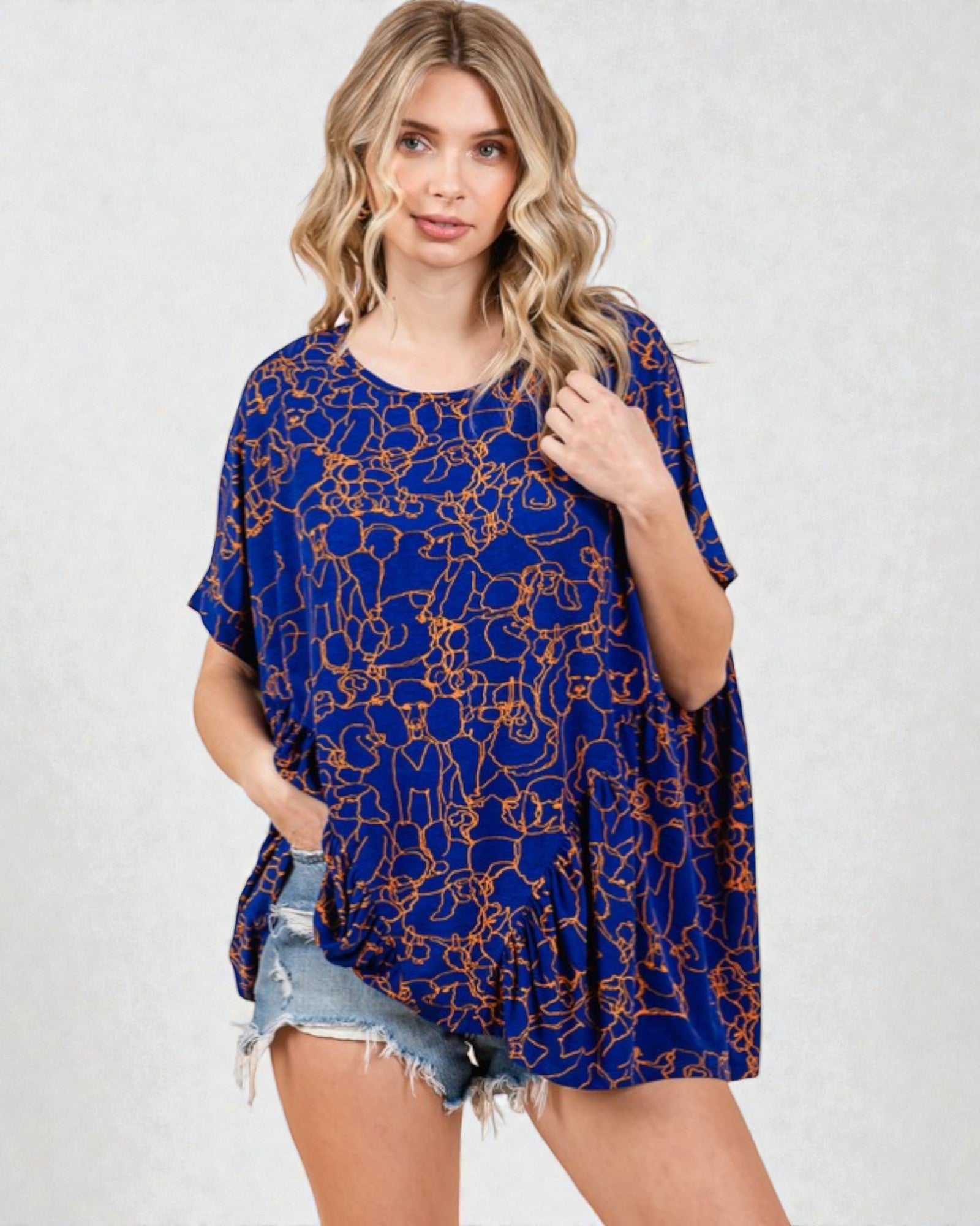 Woman wearing a blue patterned dress with denim shorts on a white background