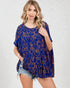 Woman wearing a blue patterned dress with denim shorts on a white background