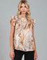 Woman wearing a patterned top with ruffled sleeves against a gray background