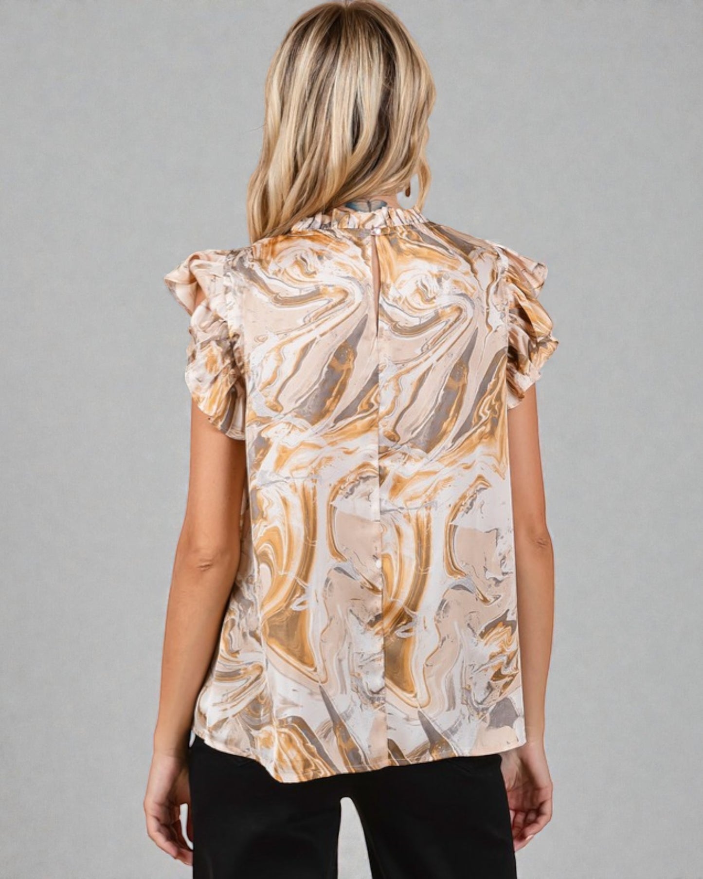 Woman wearing a patterned blouse against a gray background