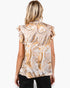A woman viewed from the back wearing a short-sleeve blouse with a beige, gold, and white marble swirl pattern and ruffled shoulders, paired with black pants, against a plain white background.