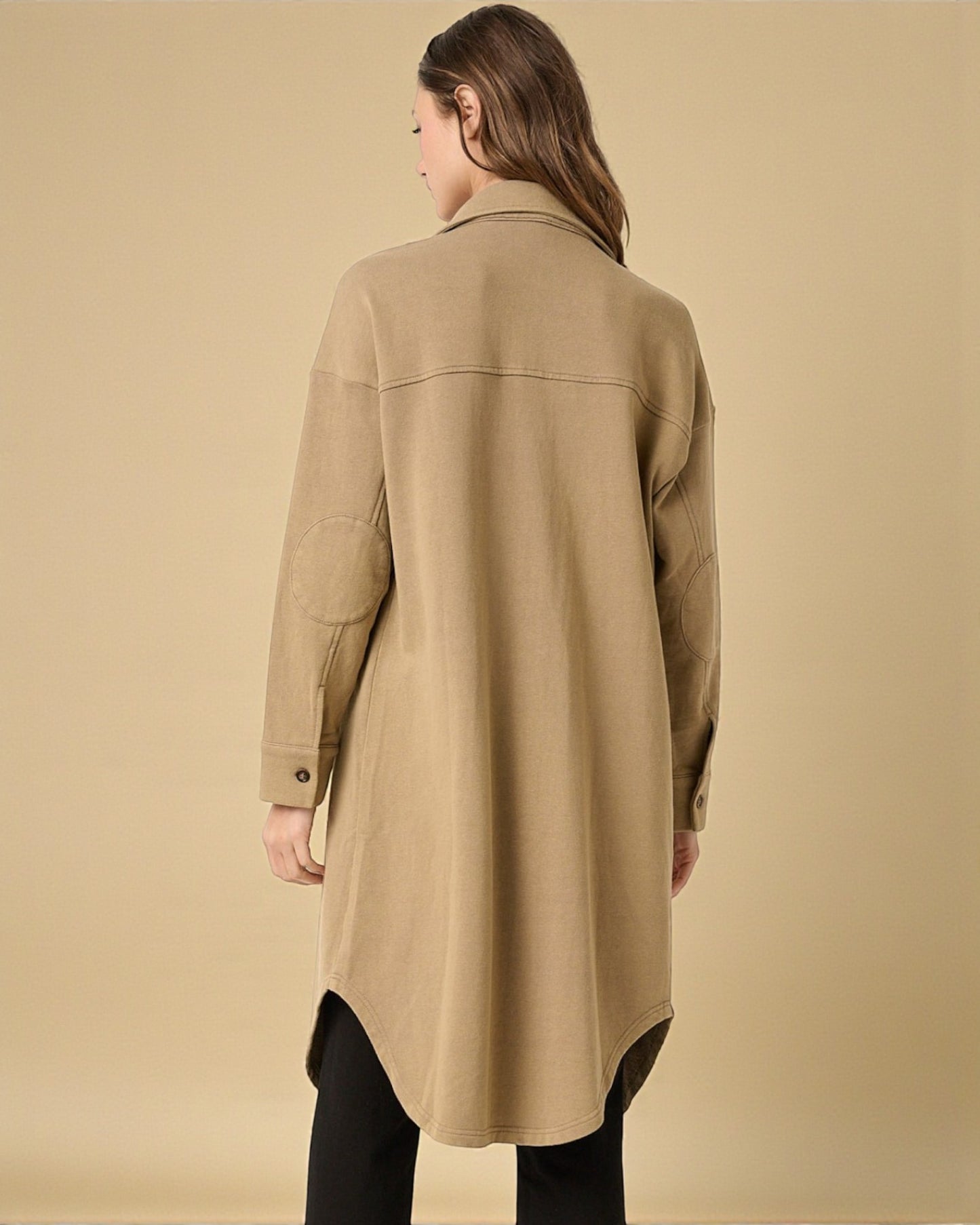Woman wearing a beige coat against a beige background