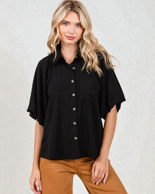 Woman wearing a black short-sleeve blouse with buttons on a light gray background