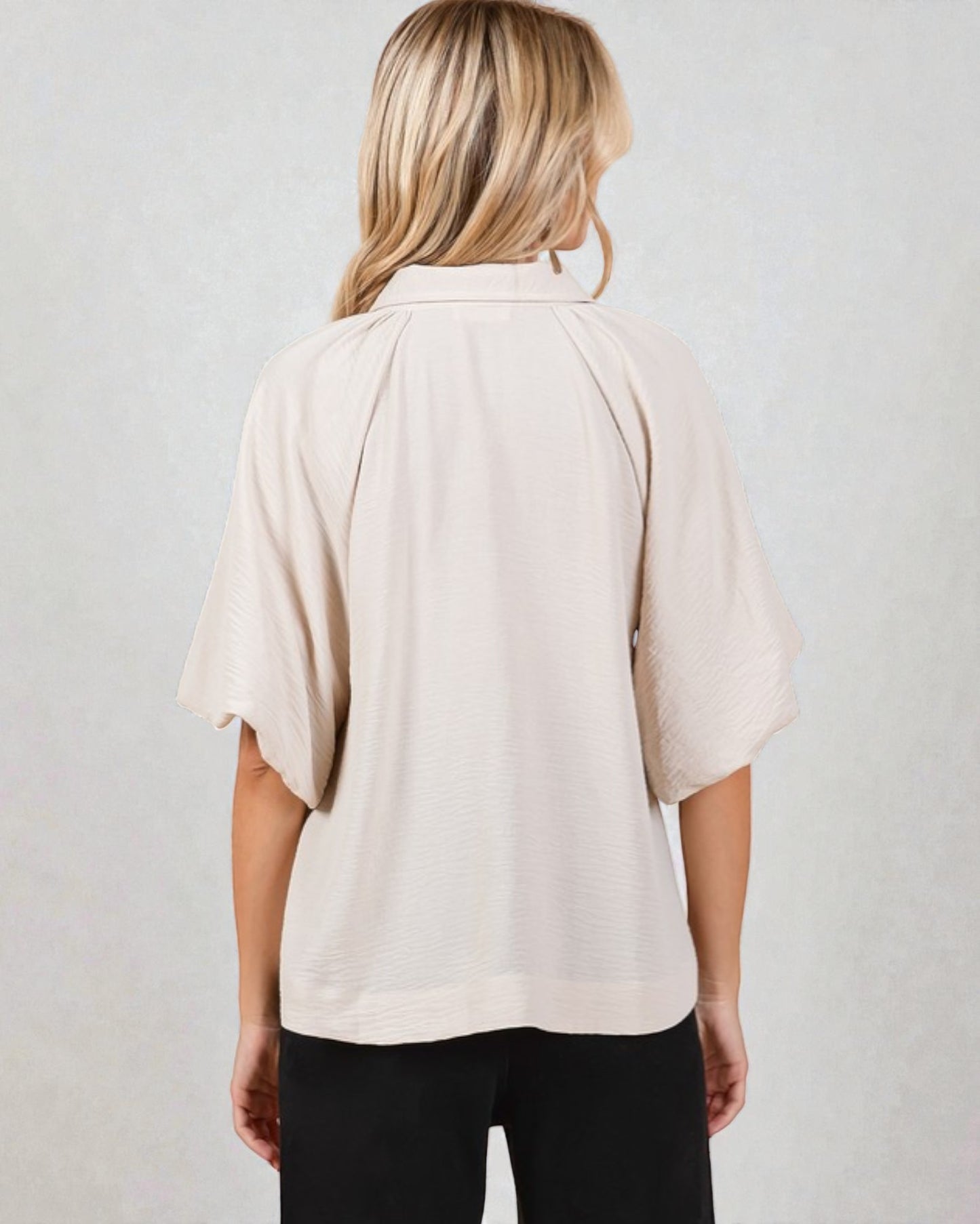 Person wearing a beige blouse with a plain background