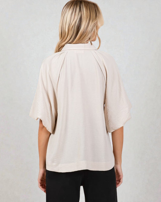 Person wearing a beige blouse with a plain background