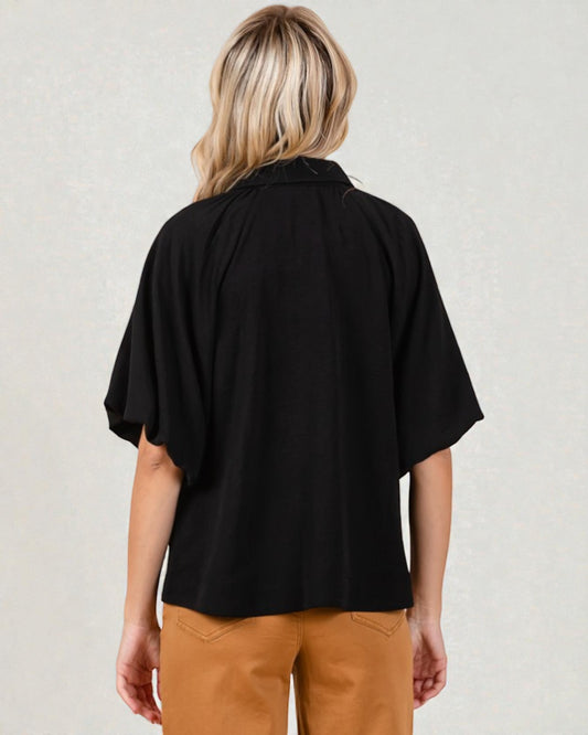 Person wearing a black top and brown pants on a plain background