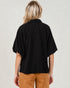 Person wearing a black top and brown pants on a plain background