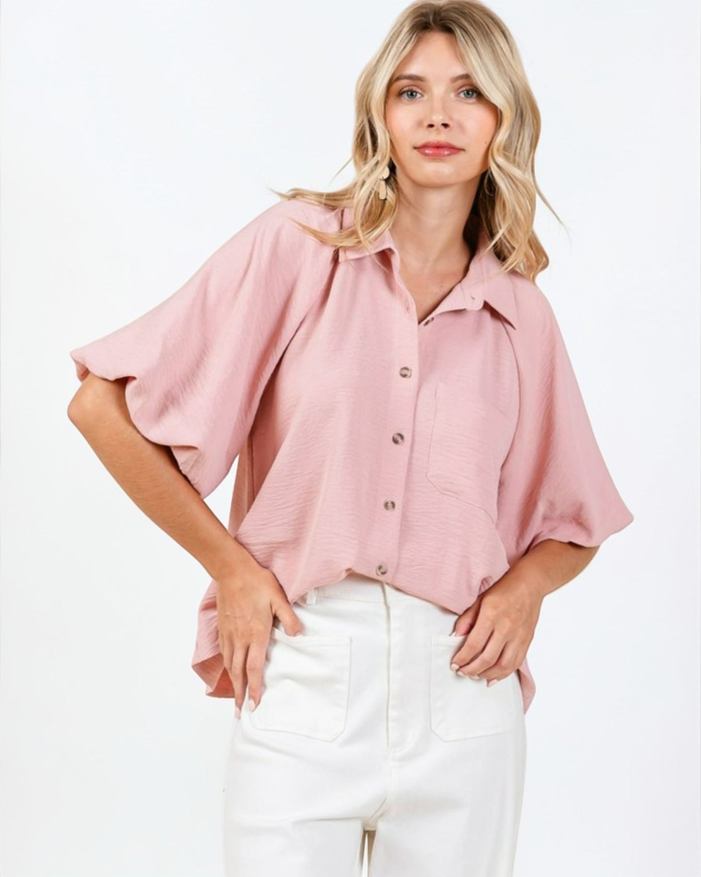 Woman wearing a pink blouse with ruffled sleeves on a white background
