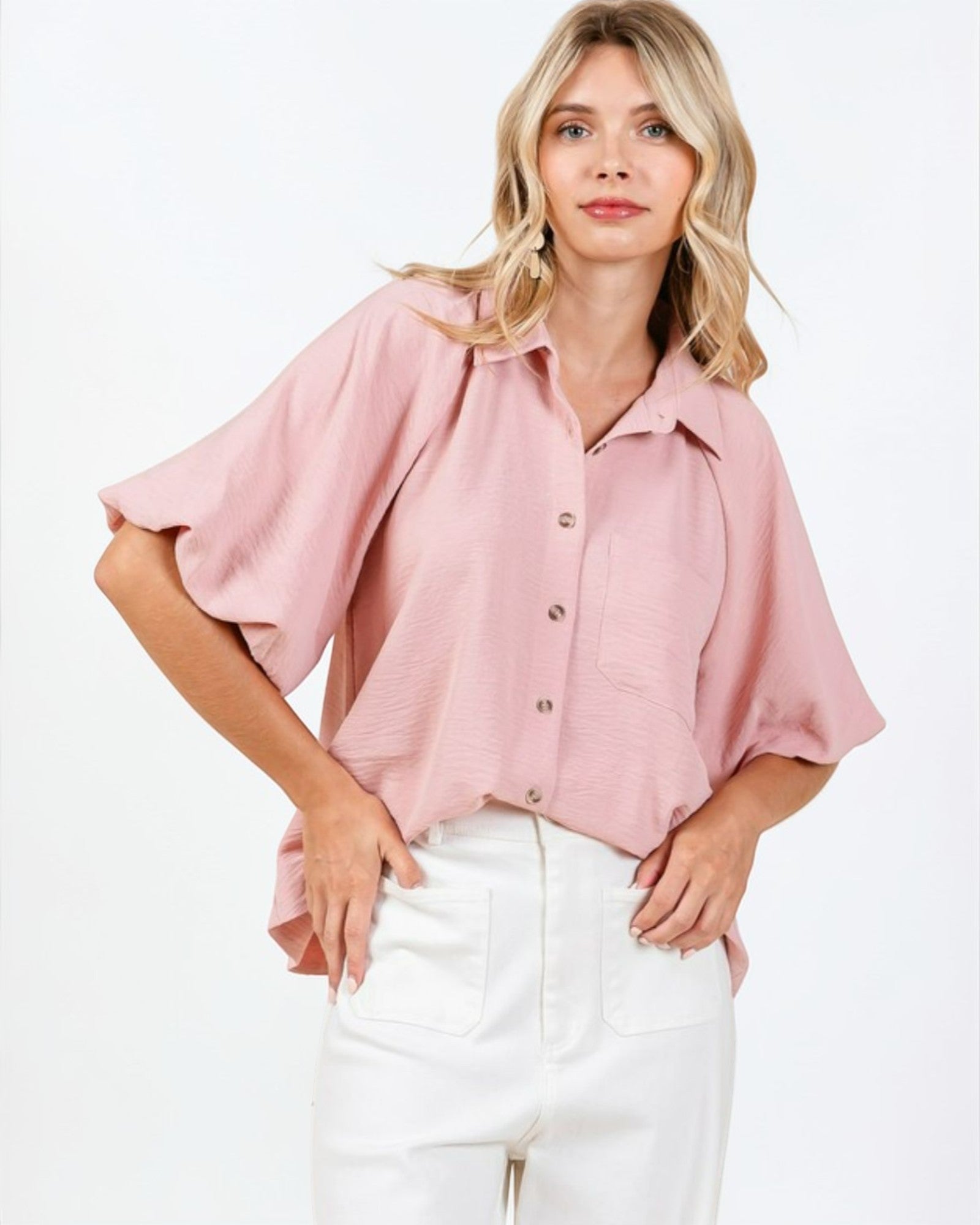 Woman wearing a pink blouse with ruffled sleeves on a white background