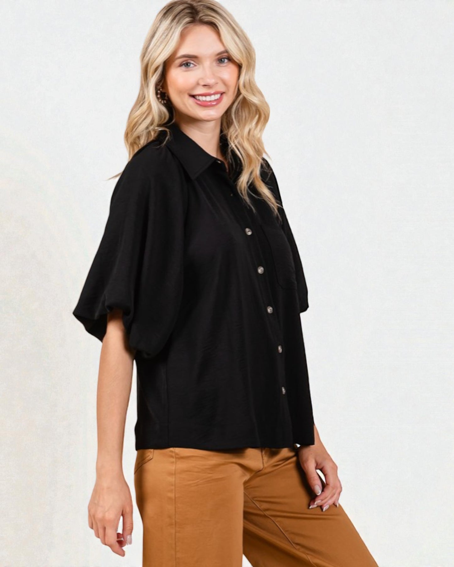 Woman wearing a black blouse and tan pants on a white background
