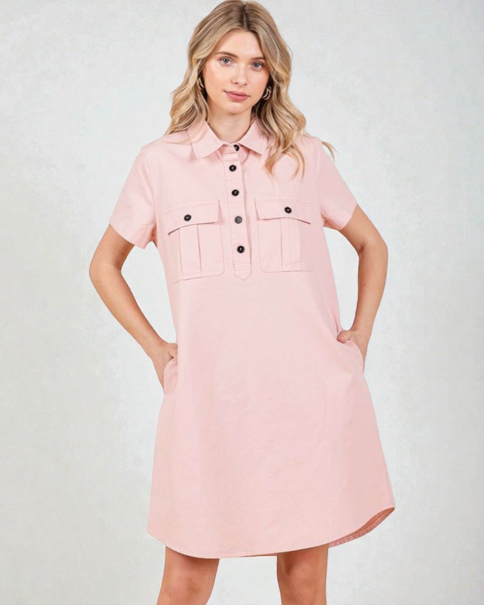 Woman wearing a pink dress with black buttons on a white background