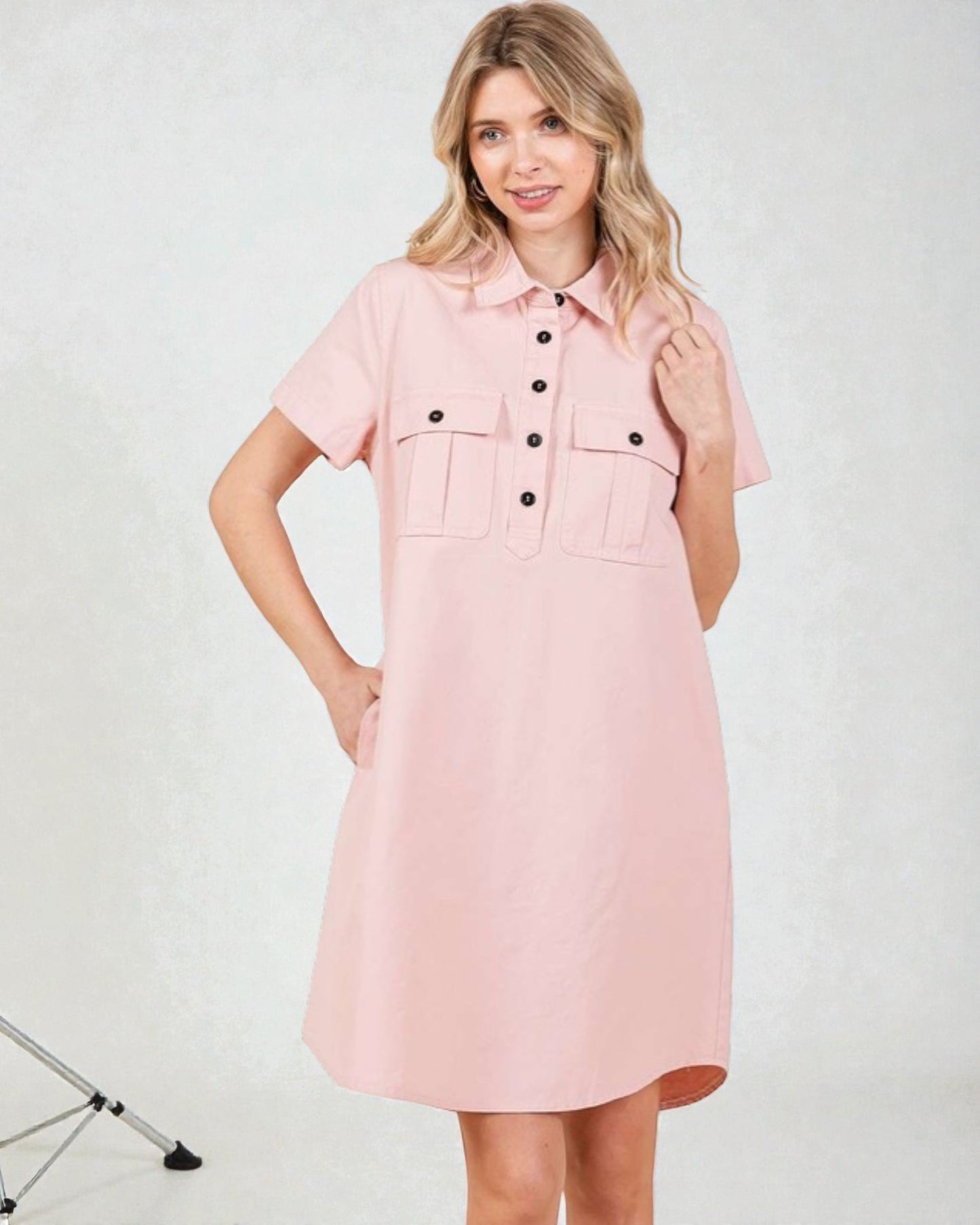 Woman wearing a pink dress with black buttons on a white background