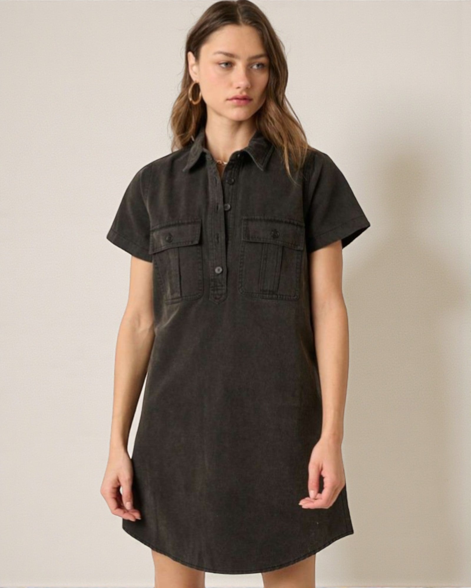 Woman wearing a black short-sleeve dress against a beige background