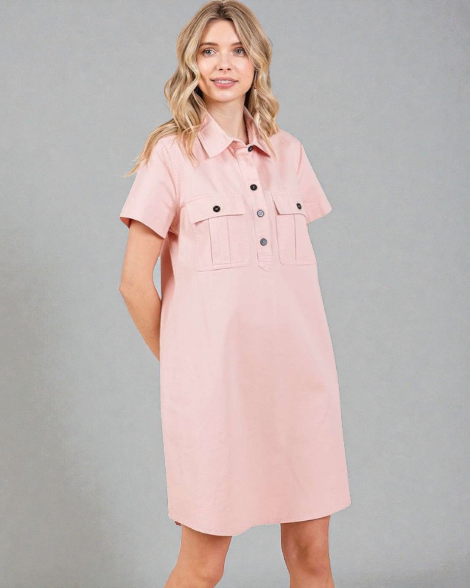 Woman wearing a pink dress with button details against a gray background