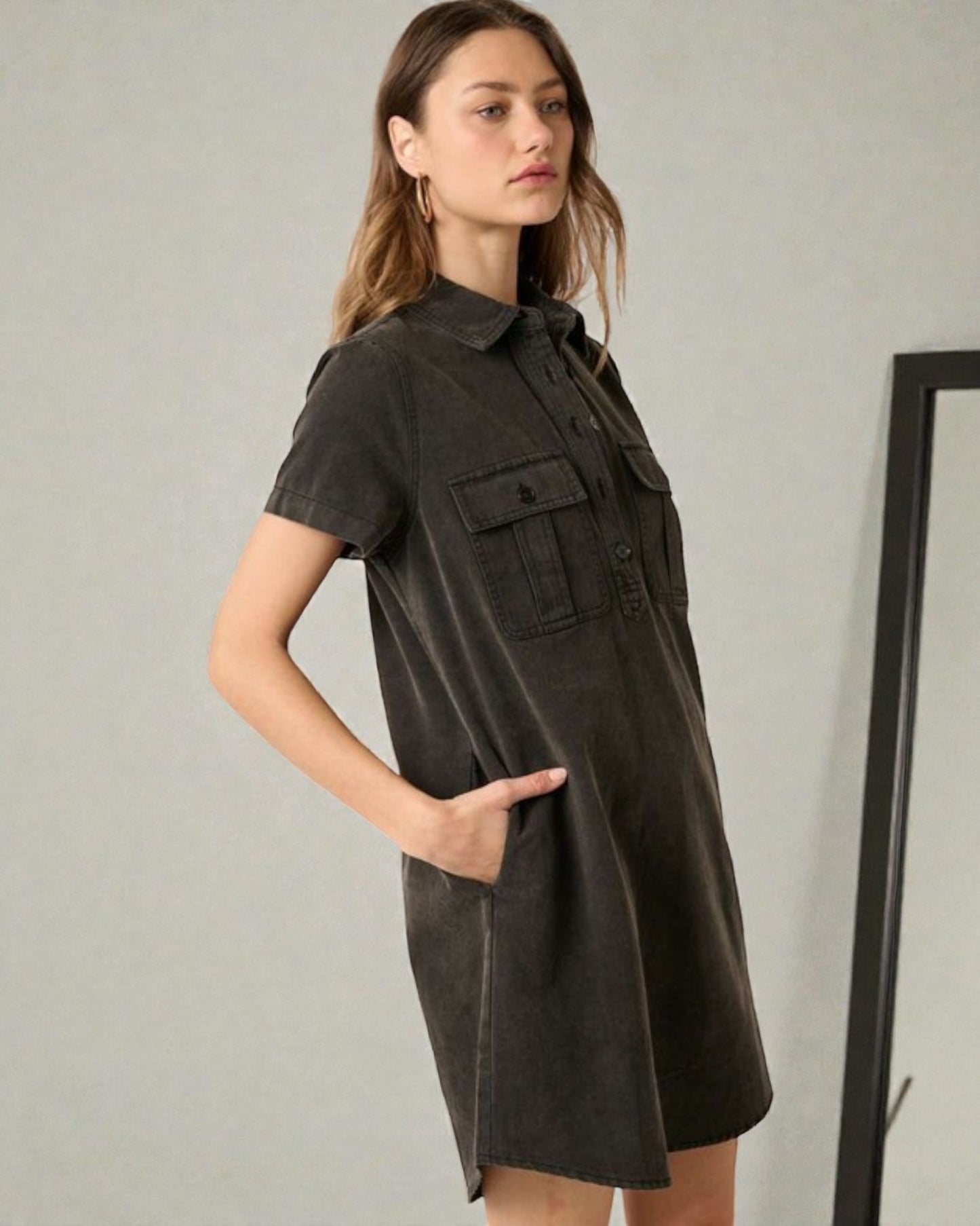 Woman wearing a dark brown dress with short sleeves and pockets against a plain background