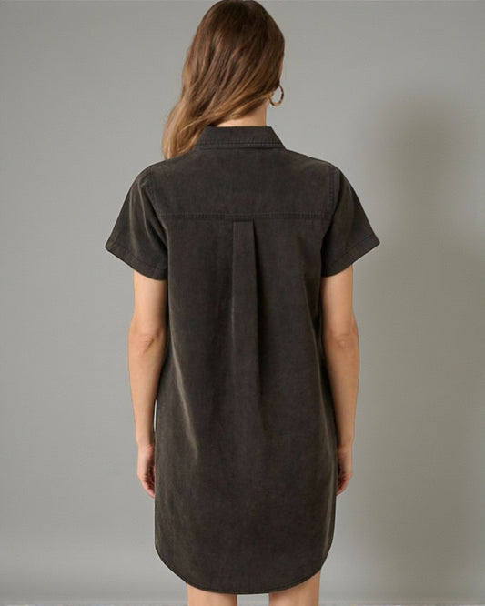 Woman wearing a dark brown shirt dress against a gray background