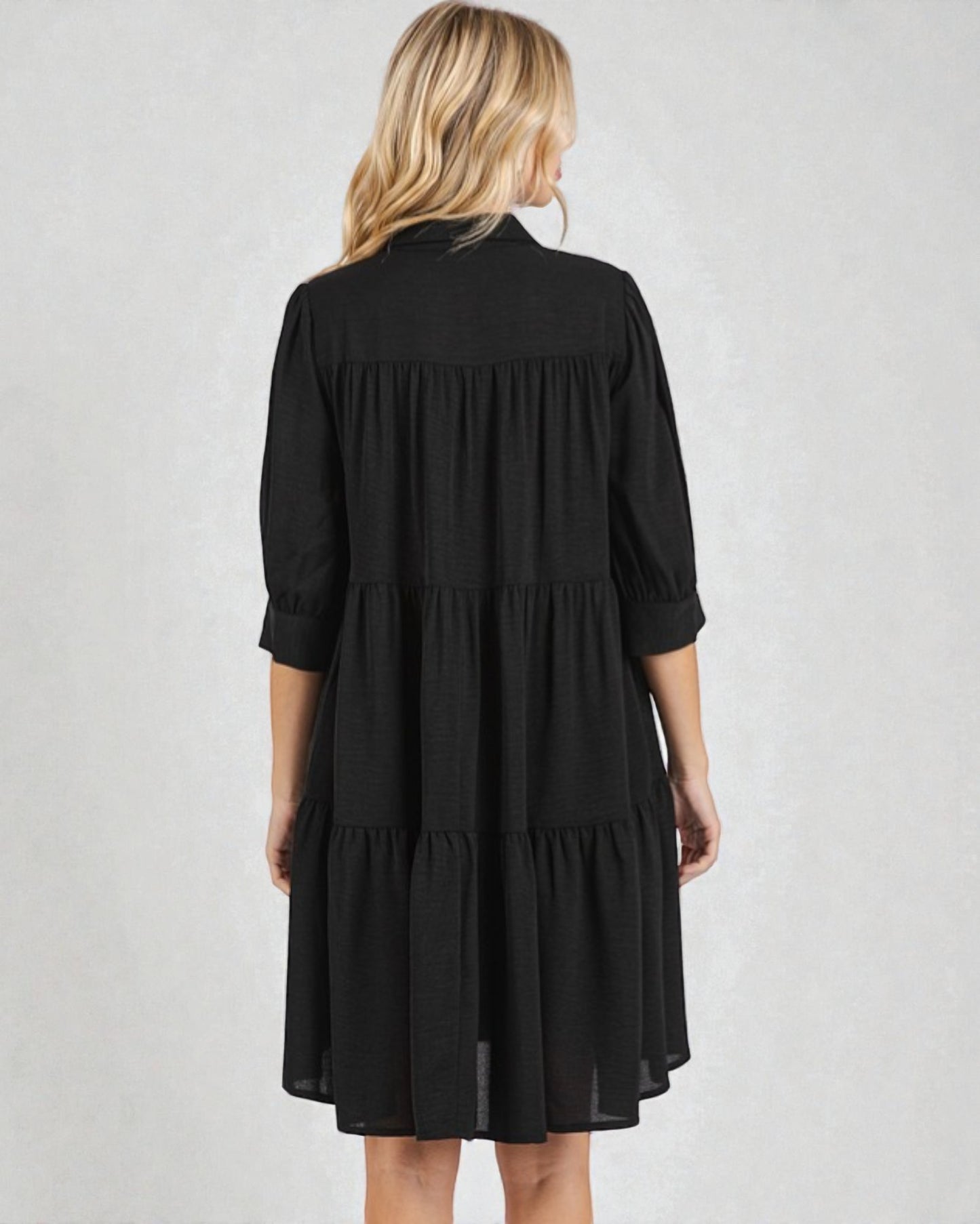 Black tiered dress worn by a person on a plain background
