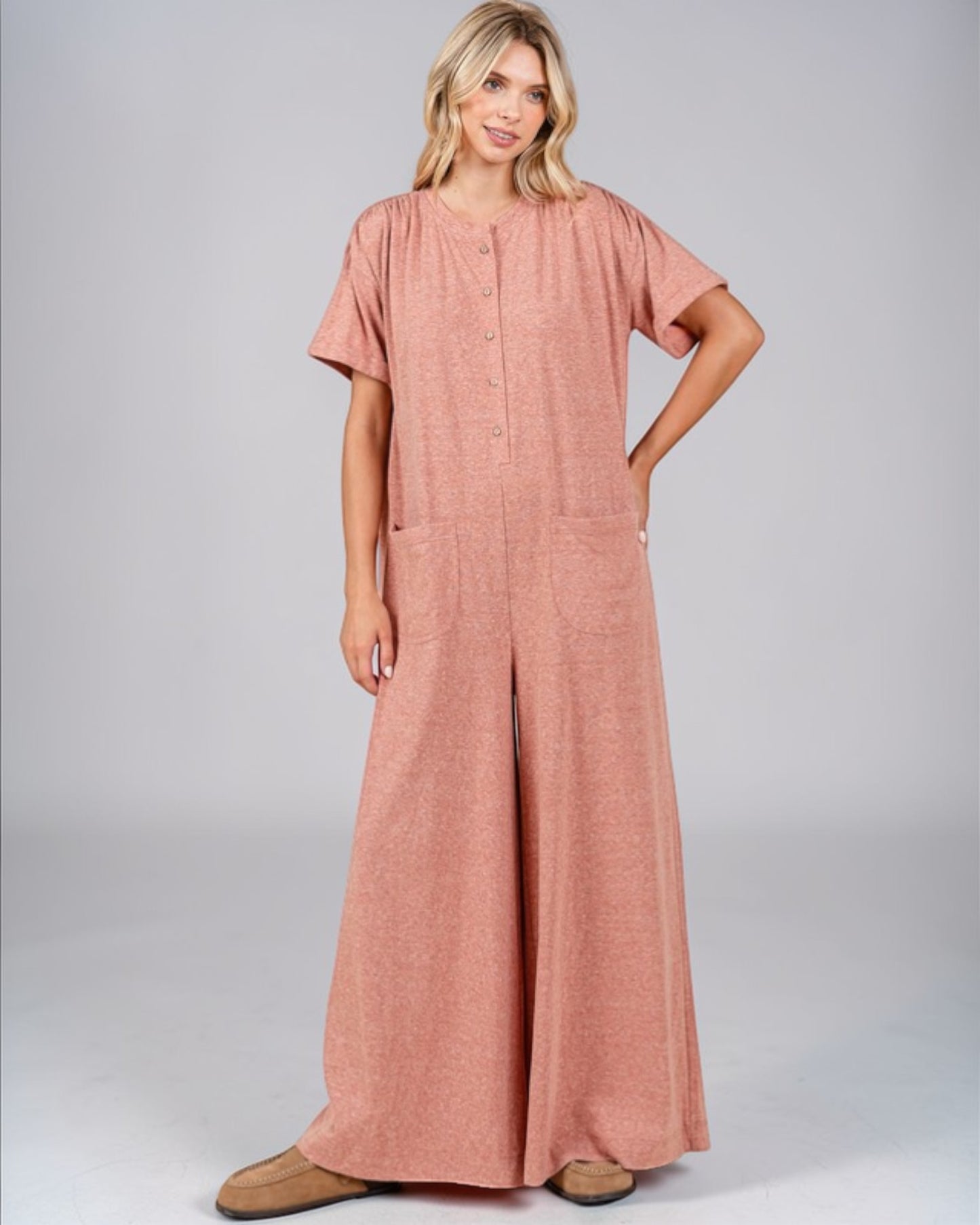 Woman wearing a pink jumpsuit on a gray background