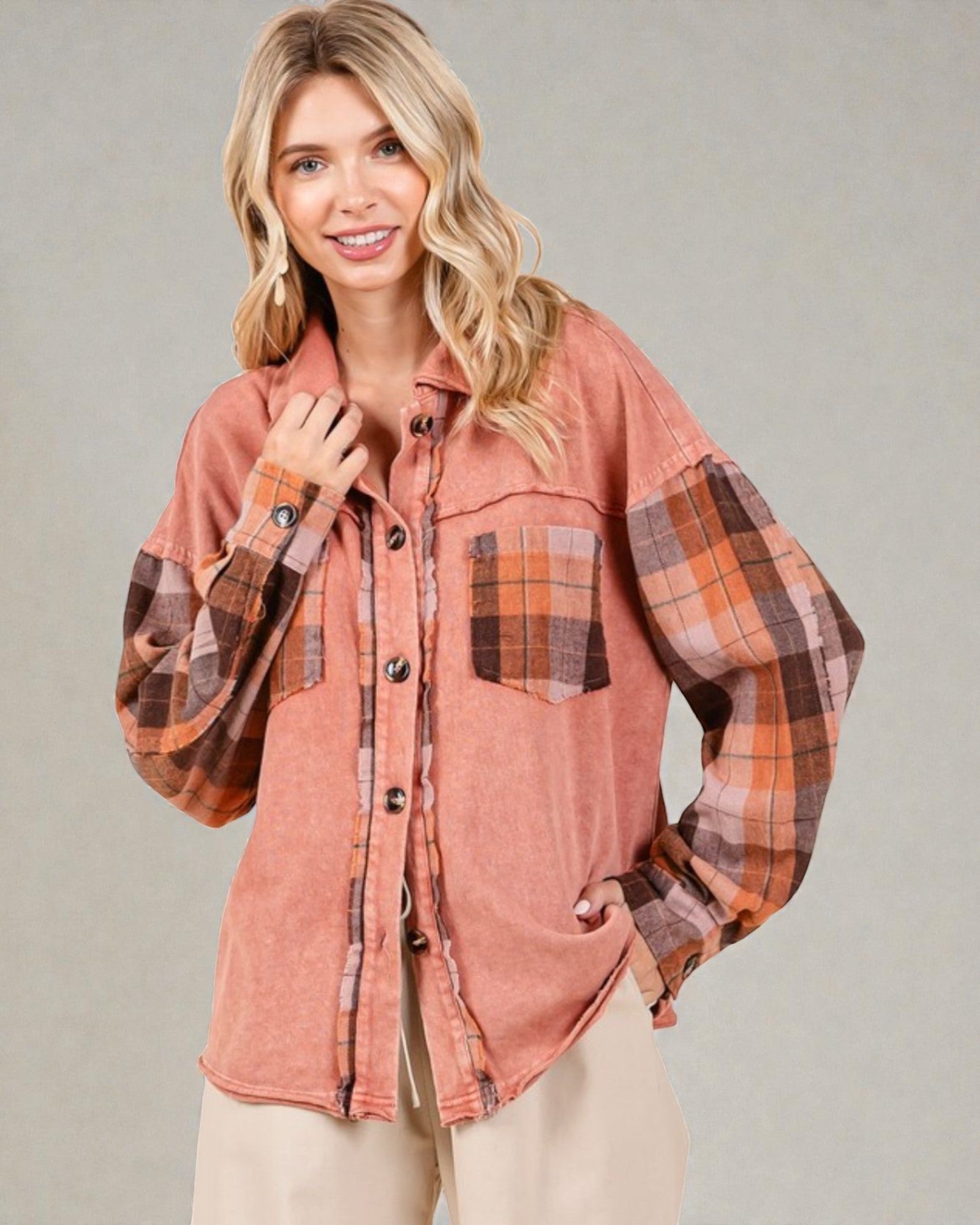 Woman wearing a plaid shirt with a pinkish-brown color scheme on a gray background