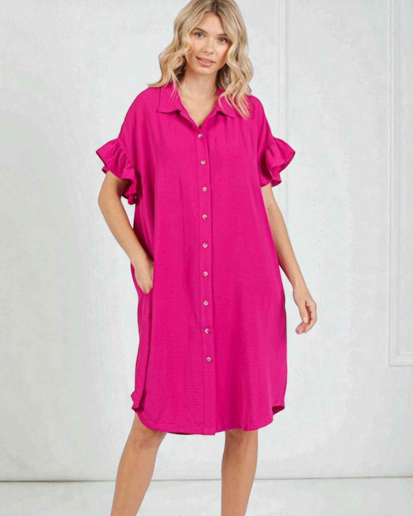 Woman wearing a bright pink dress with ruffled sleeves on a white background