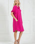Woman wearing a bright pink dress with ruffled sleeves against a white background