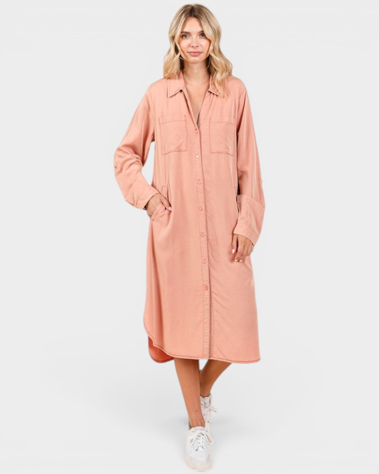 Woman wearing a long peach coat on a white background