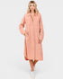 Woman wearing a long peach coat on a white background