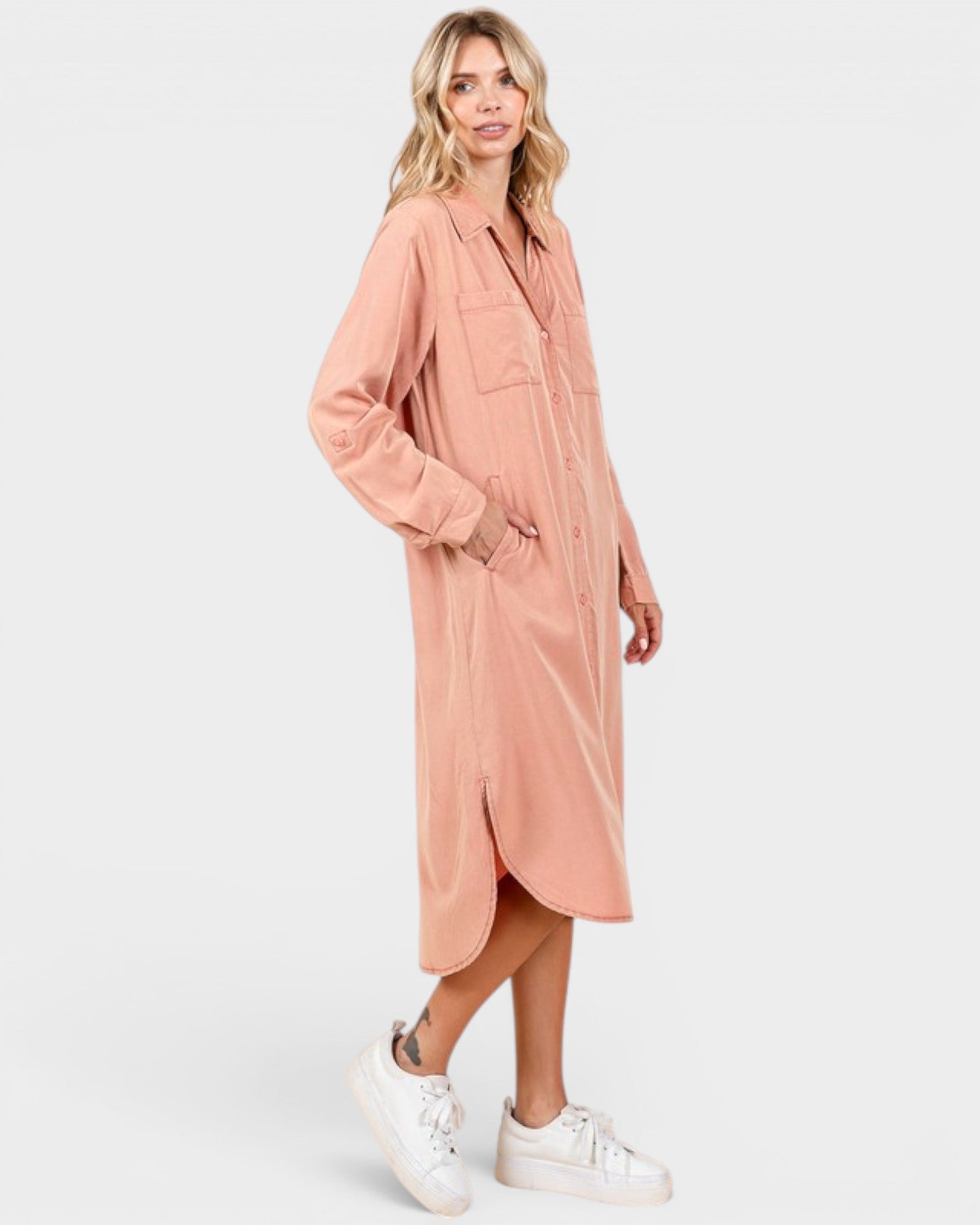 Woman wearing a long pink cardigan over a dress on a white background