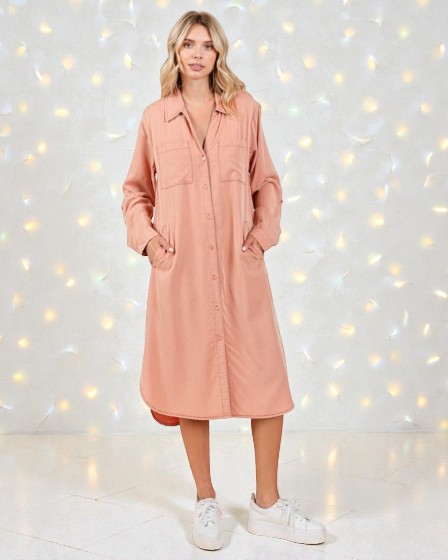 Woman wearing a pink dress with a white background and string lights