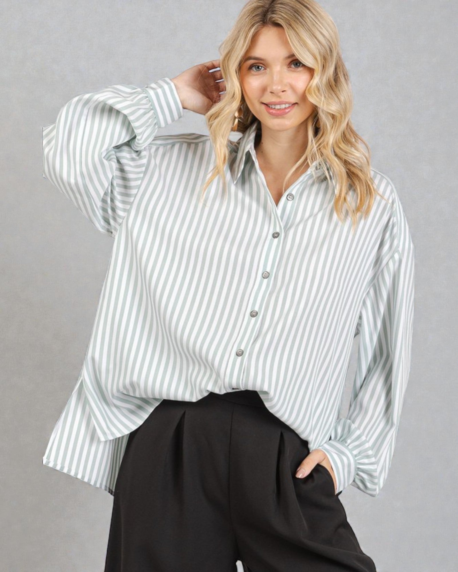 Woman wearing a striped shirt and black pants against a gray background
