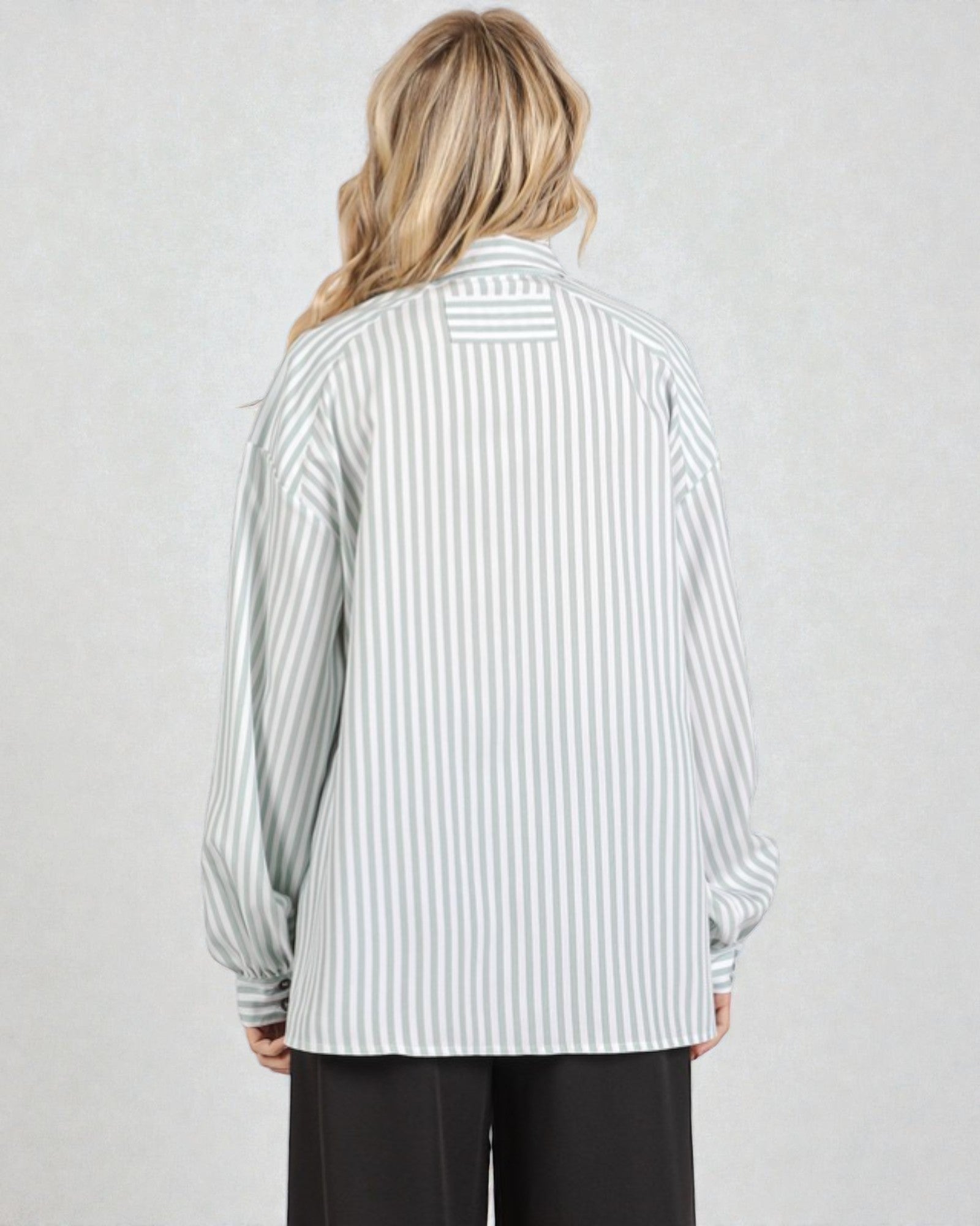 Person wearing a striped shirt with long sleeves on a plain background