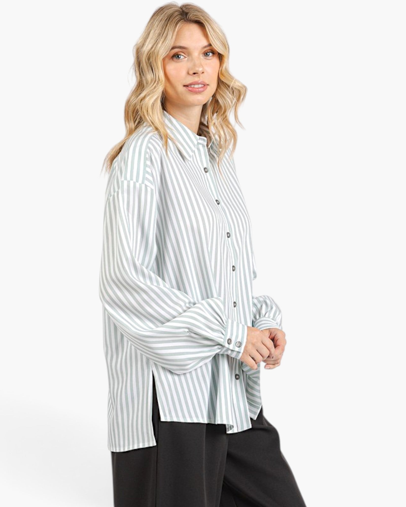 A woman modeling a light blue and white vertically striped button-up shirt with long bell sleeves, paired with black pants, against a plain white studio background.