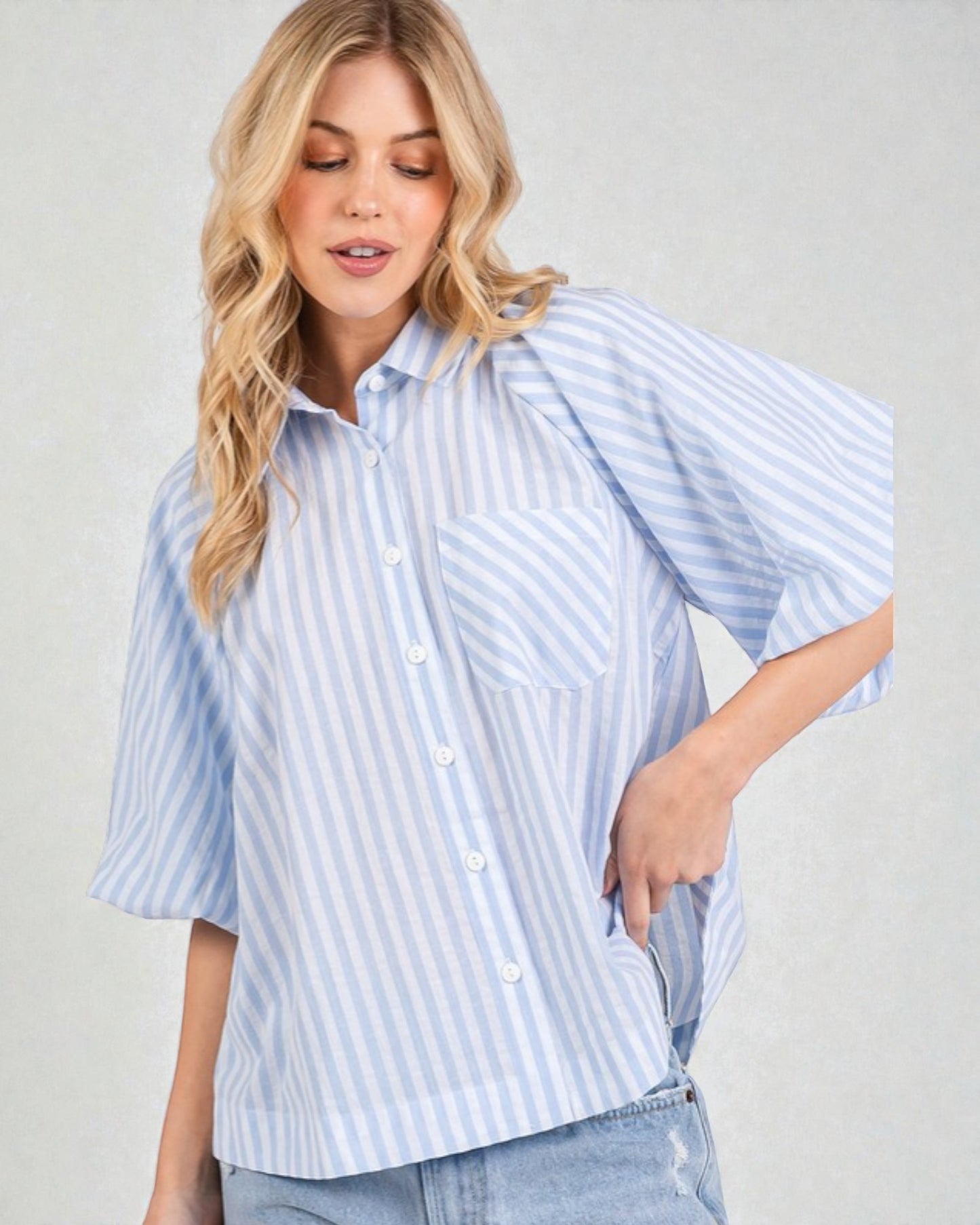 Woman wearing a light blue and white striped shirt against a plain background