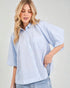 Woman wearing a light blue and white striped shirt against a plain background