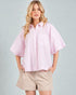 Woman wearing a light pink striped shirt and beige shorts on a gray background